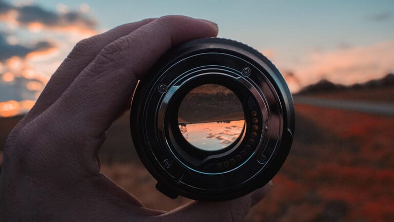 Lente para fotografía en manos de un hombre enfocando un paisaje