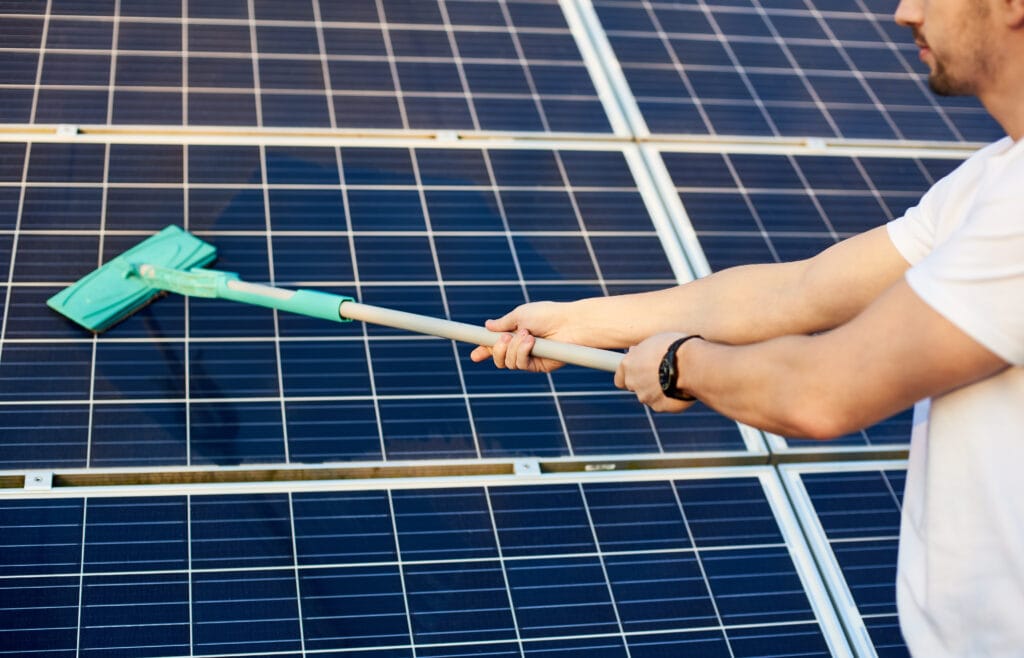 Hombre en acción de limpiar los paneles solares